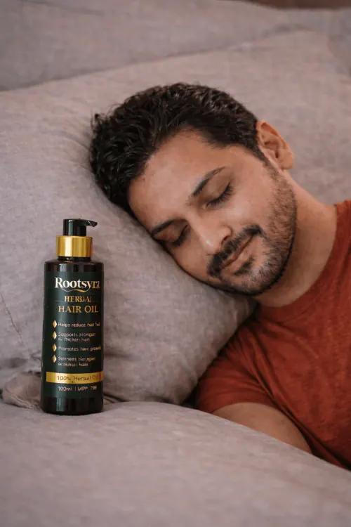Resting overnight with hair treated by Rootsyra Herbal Hair Oil, bottle beside the pillow.